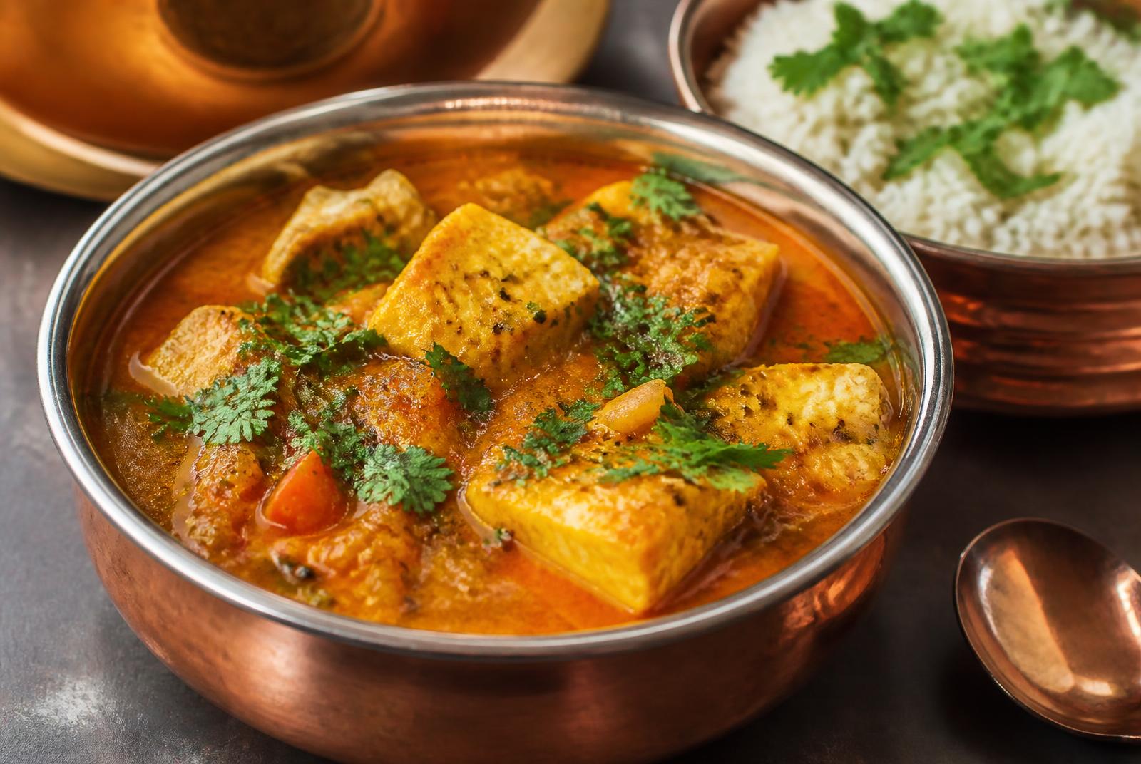 Cape Malay fish curry in a copper bowl with basmati rice and fresh coriander